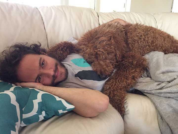 man with dog sleeping on couch.